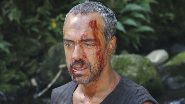 A close-up photo of the Man in Black with blood and bruises on his face.